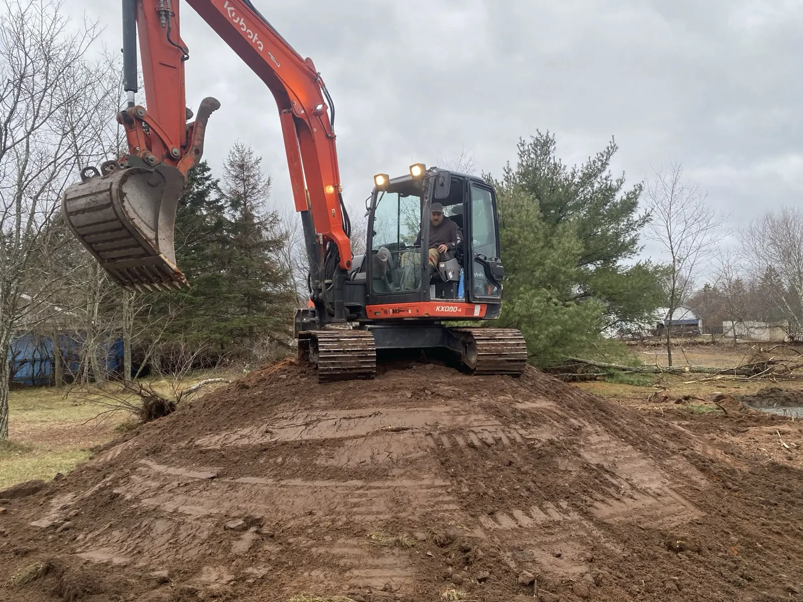 Excavator clearing and grading a residential site
