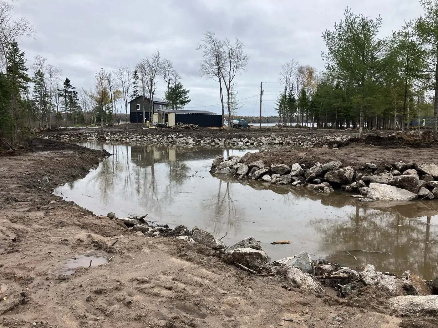 New pond edged with large rock for drainage and erosion control